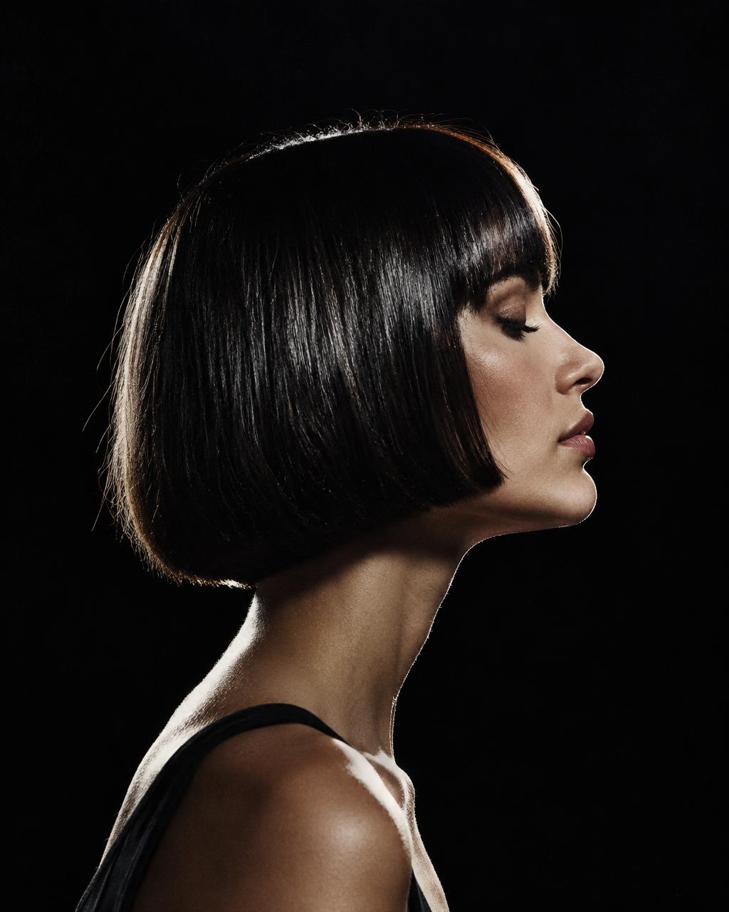 A precise short bob held in profile against black